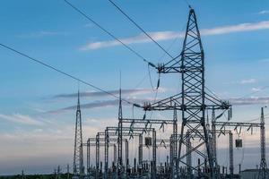 Silhouette of the high voltage electric pylon towers on the background of beautiful evening clouds photo