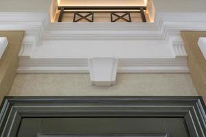 Detail of corner ceiling with intricate crown molding on column with spot light photo