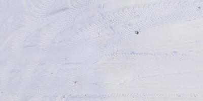 panorama view from above on texture of snow covered road with car tire tracks and footprints photo