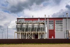 Modern Granary elevator and seed cleaning line. Silver silos on agro-processing and manufacturing plant for processing drying cleaning and storage of agricultural products, flour, cereals and grain. photo