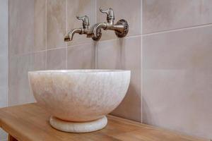 metal water tap sink with faucet in expensive bathroom. detail of a corner toilet with wall mount shower attachment photo