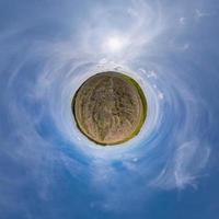 tiny planet in blue sky with beautiful clouds. Transformation of spherical panorama 360 degrees. Spherical abstract aerial view. Curvature of space. photo