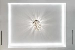 looking up on suspended ceiling with halogen spots lamps and drywall construction in empty room in apartment or house. Stretch ceiling white and complex shape. photo