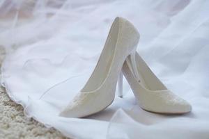 zapatos de boda blancos en velo de novia vestido blanco foto