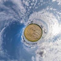 tiny planet transformation of spherical panorama 360 degrees. Spherical abstract aerial view in field with clear sky and awesome beautiful clouds. Curvature of space. photo