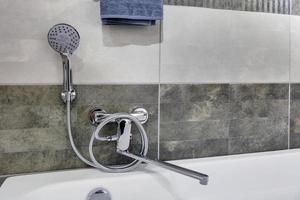 water tap sink with faucet in expensive loft bathroom. detail of a corner shower cabin with wall mount shower attachment photo