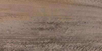 panorama of surface from above of gravel road with car tire tracks photo