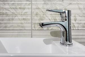 water tap sink with faucet in expensive loft bathroom. detail of a corner shower cabin with wall mount shower attachment photo