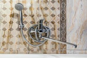 fregadero con grifo de agua en un costoso baño tipo loft. detalle de una cabina de ducha de esquina con accesorio de ducha montado en la pared foto