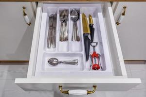 set of knives, forks and  spoons on the shelf in the kitchen cabinet