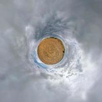 tiny planet in blue sky with beautiful clouds. Transformation of spherical panorama 360 degrees. Spherical abstract aerial view. Curvature of space. photo