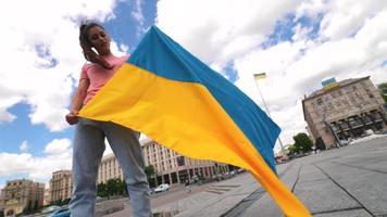 mujer joven sostiene y ondea la bandera de ucrania en el centro de Kyiv video