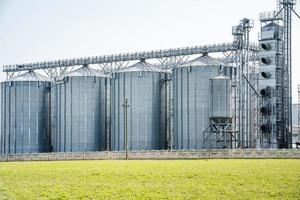 ascensor de granero moderno. silos de plata en la planta de procesamiento y fabricación de productos agrícolas para el procesamiento, secado, limpieza y almacenamiento de productos agrícolas, harina, cereales y granos. línea de limpieza de semillas foto