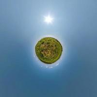 tiny planet on dandelion field in blue sky with beautiful clouds. Transformation of spherical panorama 360 degrees. Spherical abstract aerial view. Curvature of space. photo