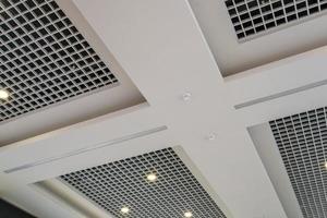 suspended and grid ceiling with halogen spots lamps and drywall construction in empty room in store or house. Stretch ceiling white and complex shape. photo