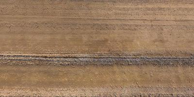 panorama of surface from above of gravel road with car tire tracks photo