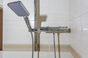 grifo de agua cuadrado con grifo en baño caro. detalle de una cabina de ducha de esquina con accesorio de ducha montado en la pared foto