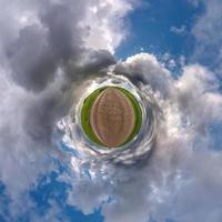 tiny planet in blue sky with sun and beautiful clouds. Transformation of spherical panorama 360 degrees. Spherical abstract aerial view. Curvature of space. photo