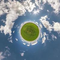 tiny planet in blue sky with sun and beautiful clouds. Transformation of spherical panorama 360 degrees. Spherical abstract aerial view. Curvature of space. photo