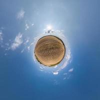 tiny planet in blue sky with sun and beautiful clouds. Transformation of spherical panorama 360 degrees. Spherical abstract aerial view. Curvature of space. photo