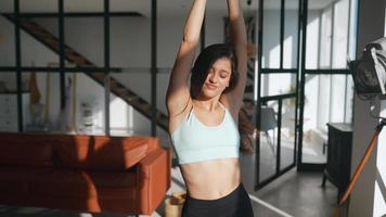 Une jeune femme en forme de vêtements de loisirs met les mains dans les cheveux et danse au soleil depuis la fenêtre video