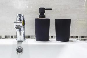 Ceramic Water tap sink with faucet with black soap and shampoo dispensers in expensive bathroom photo