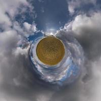 tiny planet in blue sky with beautiful clouds. Transformation of spherical panorama 360 degrees. Spherical abstract aerial view. Curvature of space. photo