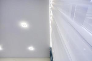 suspended ceiling with halogen spots lamps and drywall construction in empty room in apartment or house. Stretch ceiling white and complex shape. photo