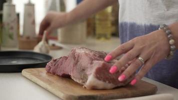Female hands salt and flavour a piece of meat. Adding salt and seasoning to beef and pork. a piece of fresh meat on a wooden board. cooking process video