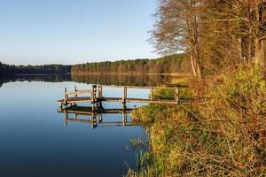 wooden pier on lake in autumn forest in evening photo