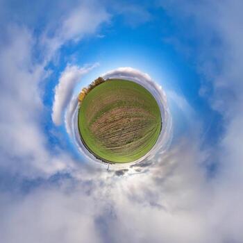 tiny planet in blue sky with sun and beautiful clouds. Transformation of spherical panorama 360 degrees. Spherical abstract aerial view. Curvature of space. photo