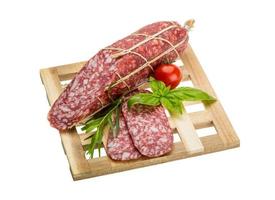 Salami on wooden plate and white background photo