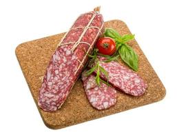 Salami on wooden plate and white background photo