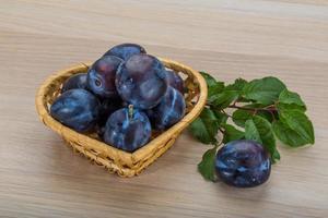 Fresh plums in a basket on white background photo