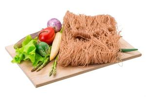 Raw rice noodles on wooden plate and white background photo