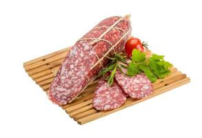 Salami on wooden plate and white background photo