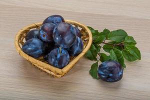 Fresh plums in a basket on white background photo