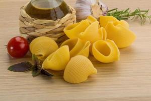 Raw pasta on wooden background photo