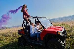 gente emocionada divirtiéndose disfrutando de un hermoso día soleado sosteniendo antorchas coloridas mientras conduce un coche de buggy fuera de la carretera foto