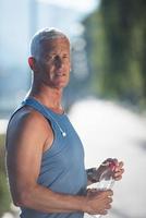 senior jogging man drinking fresh water from bottle photo