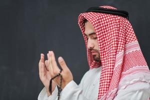 Arab man in traditional clothes praying to God or making dua photo