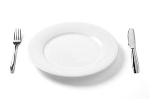 Empty plate with knife and fork isolated on a white background. photo