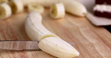 slicing a ripe yellow banana into pieces during cooking photo