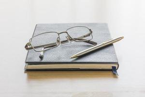 libro negro con gafas y bolígrafo foto