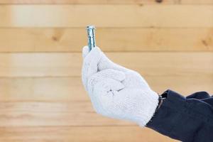 Hand in glove holding metal anchor bolts photo