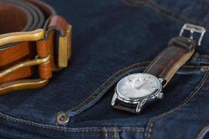 Wrist watch and leather belt on jeans photo