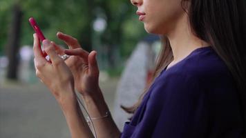 Young brunette woman uses smart phone scrolling and tapping screen in a public space video