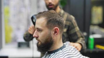 Barber trims hair of male client with comb and clippers video