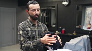 Barber wraps client's face with warm towel and while talking video