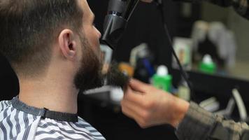 Barber used hair dryer and round brush to shape and style man's beard video